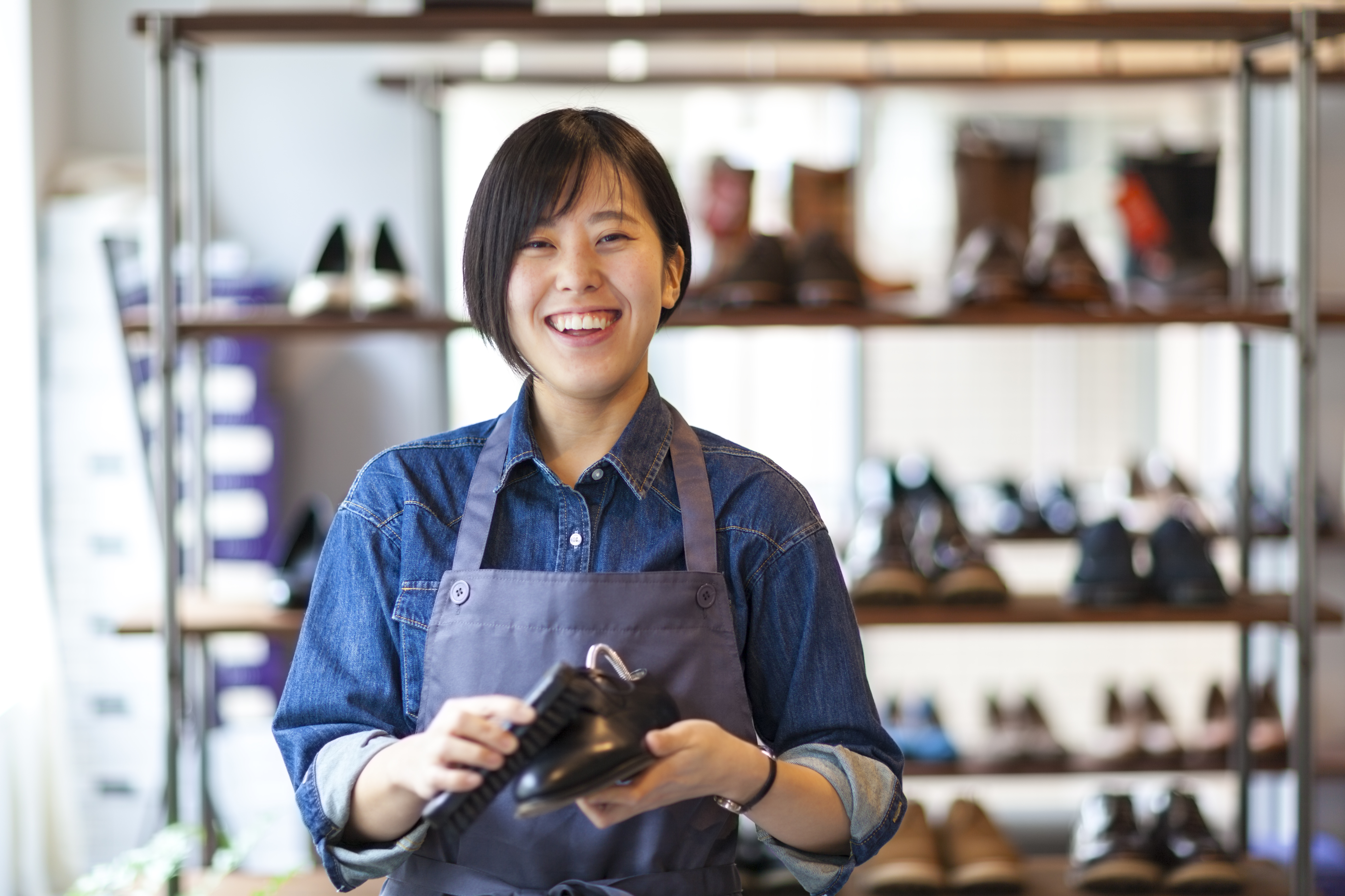 person smiling at camera while polishing shoe