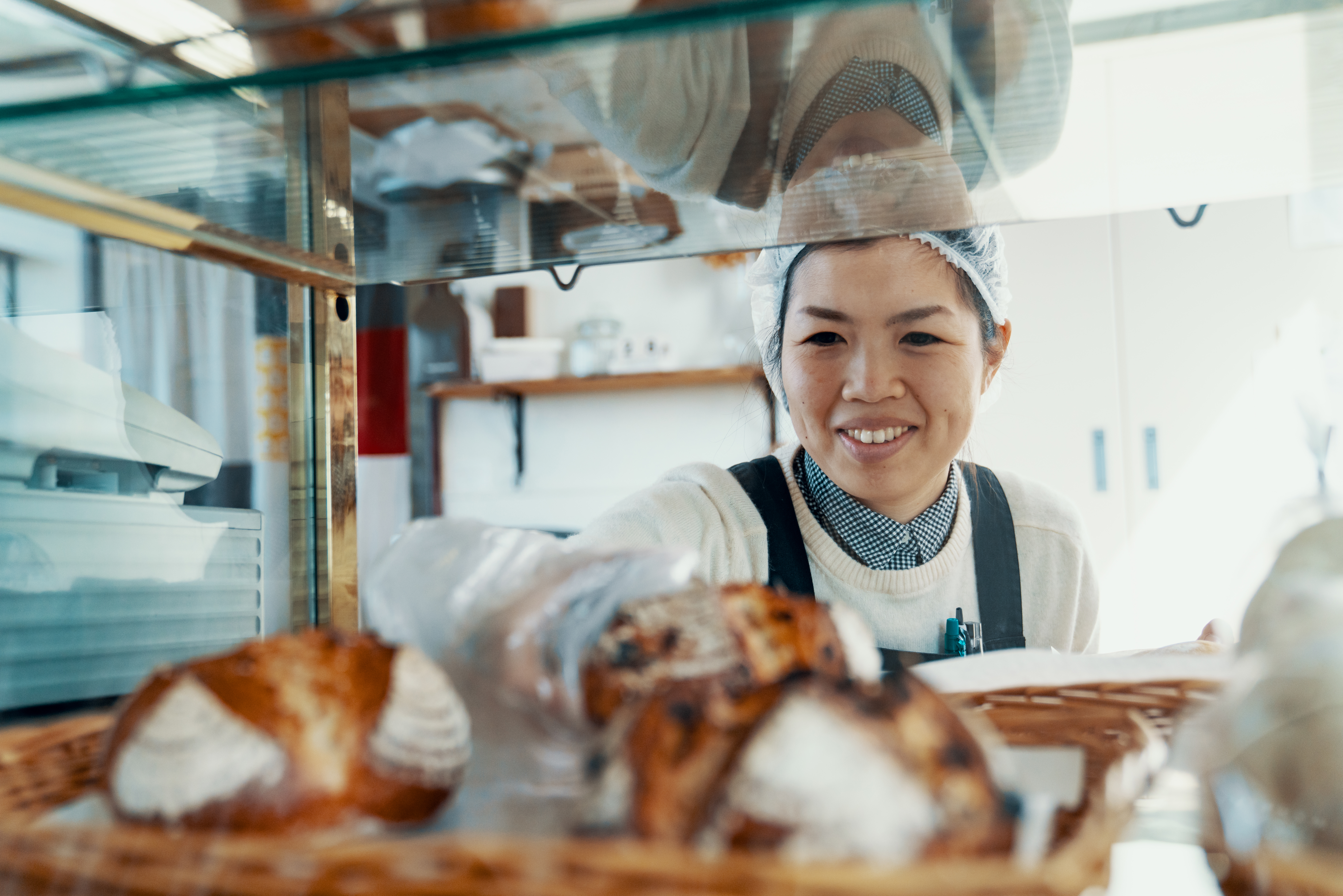 Woman with hair net reaching in for food